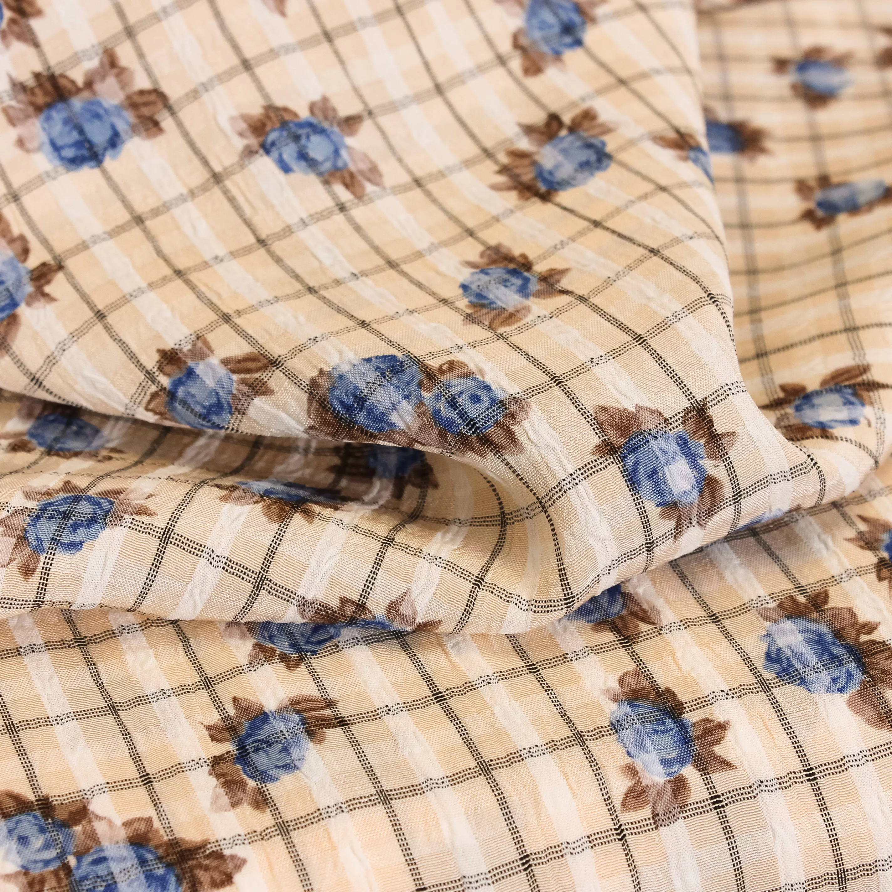 Bleke huidskleurige viscose met ingeweven ruiten en blauwe rozen