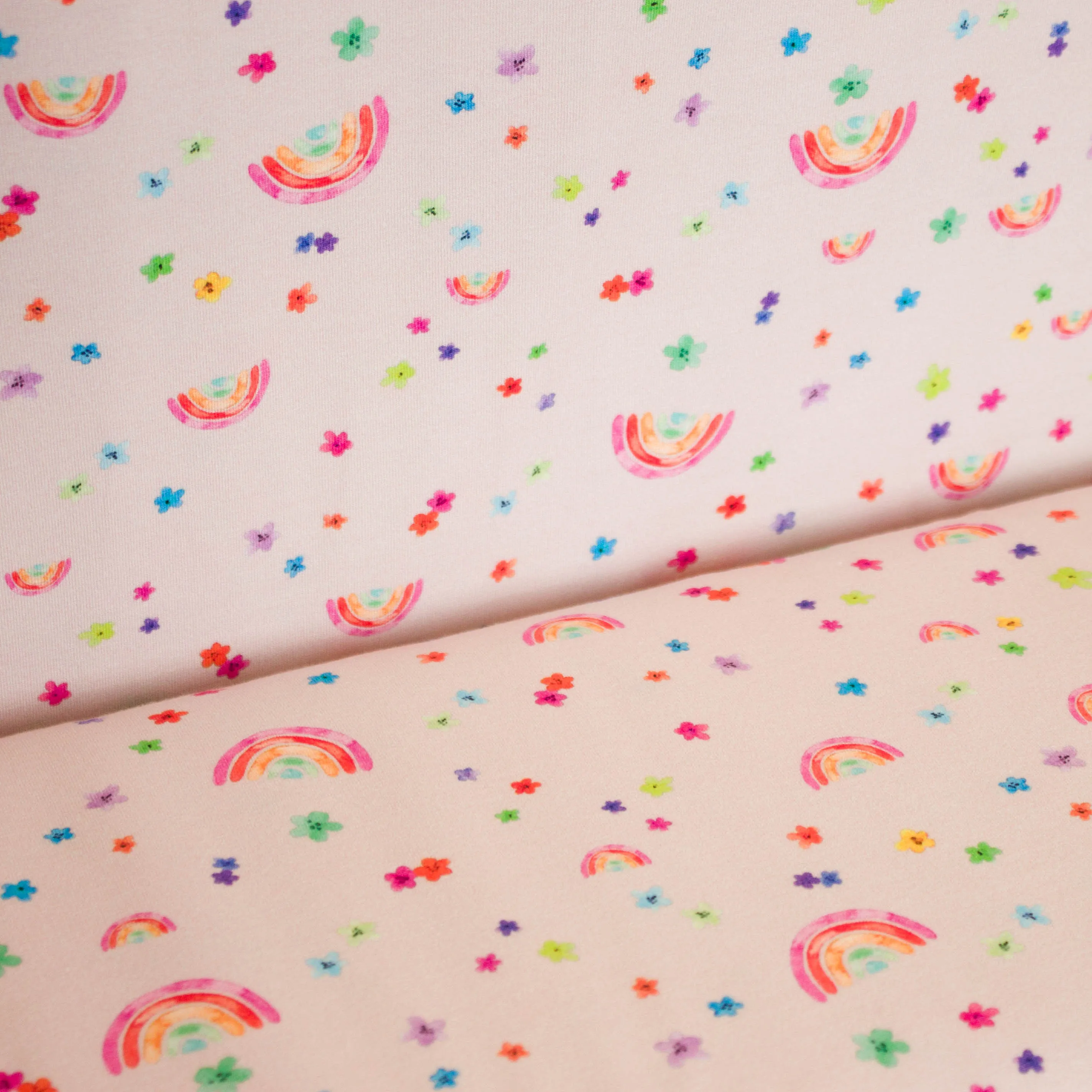 Tricot lichtroze met regenboogjes en bloemetjes