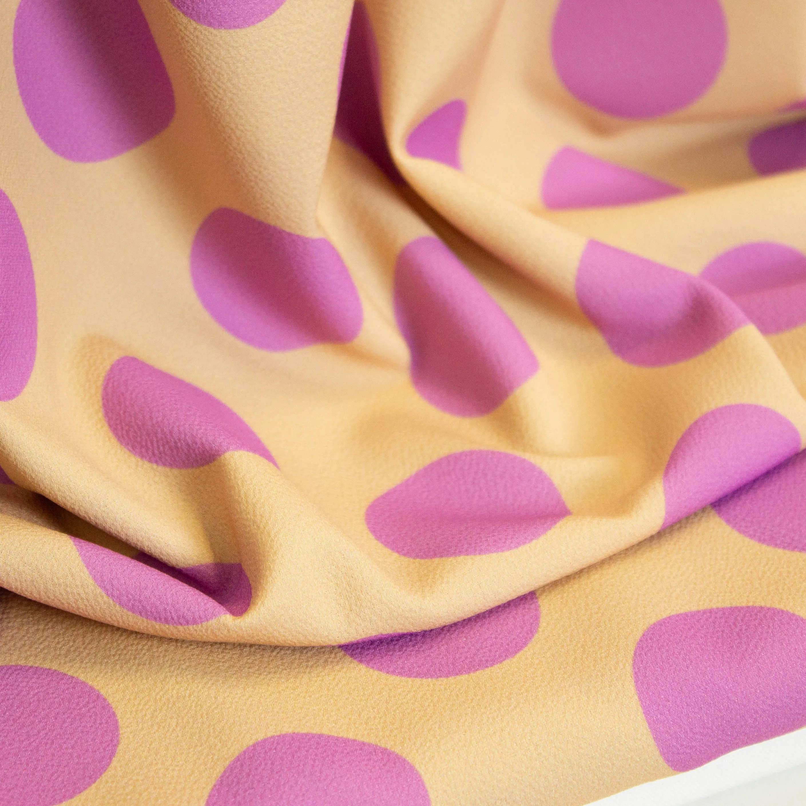 Polyester crêpe beige met paarse bollen