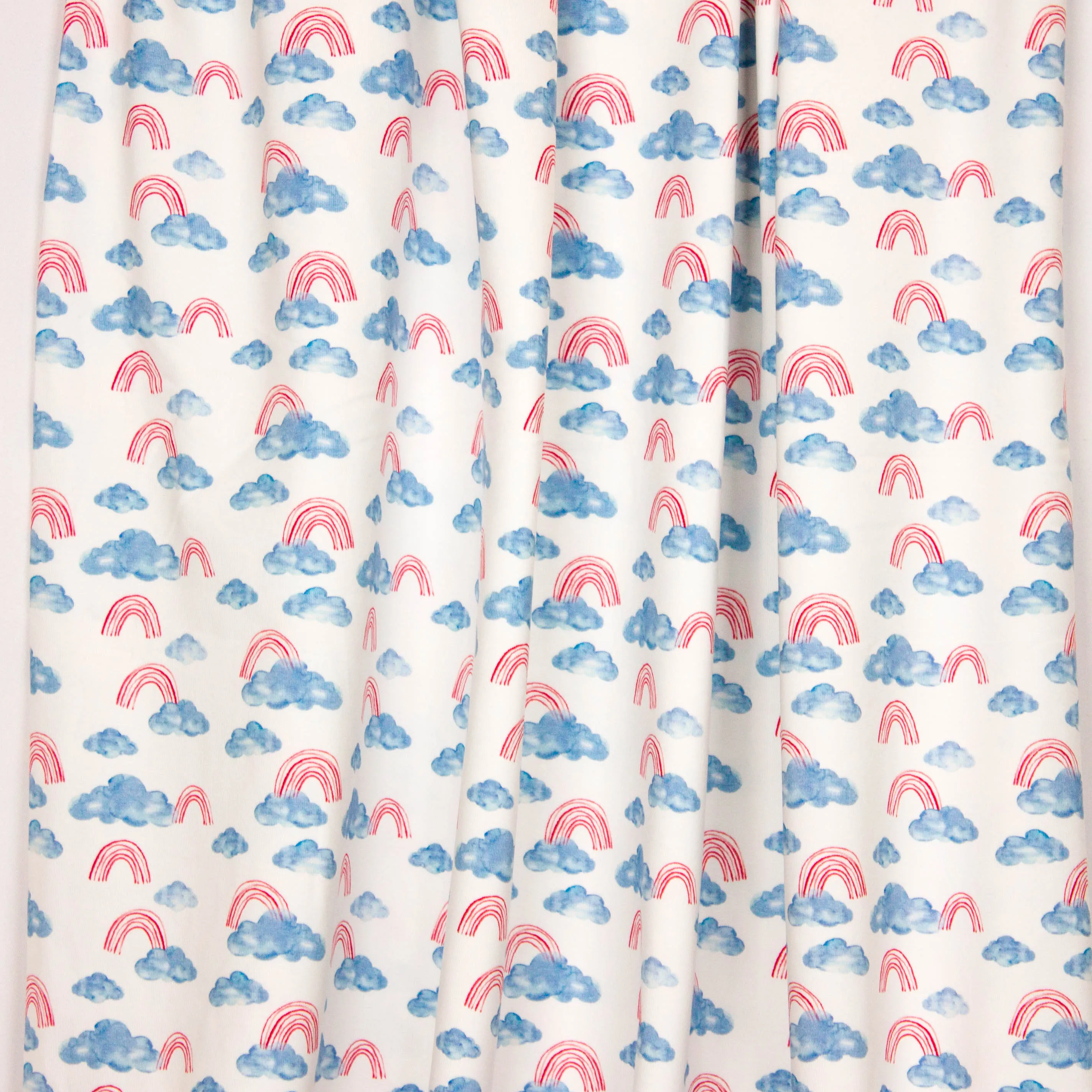 Witte tricot met blauwe wolken en rode regenbogen